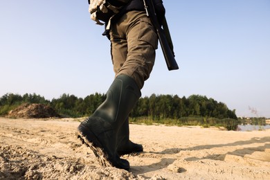 Man with hunting rifle and backpack outdoors, closeup