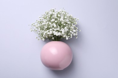 Bouquet of white gypsophila in ceramic vase on light background, top view