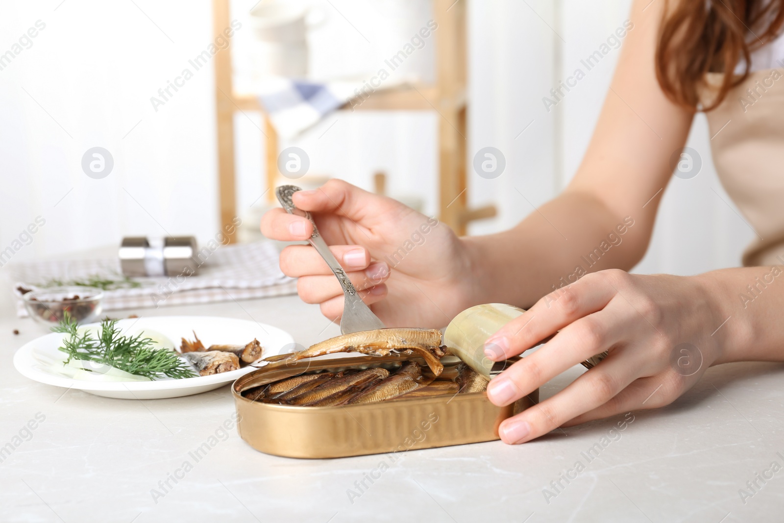 Photo of Woman with tin can of conserved fish at table