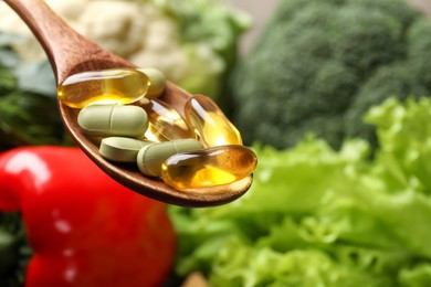 Photo of Dietary supplements. Spoon with pills over food products, closeup