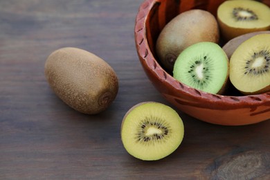 Photo of Whole and cut fresh kiwis on wooden table, closeup