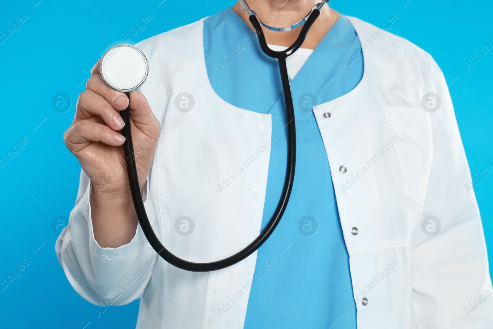 Photo of Mature doctor with stethoscope on blue background, closeup