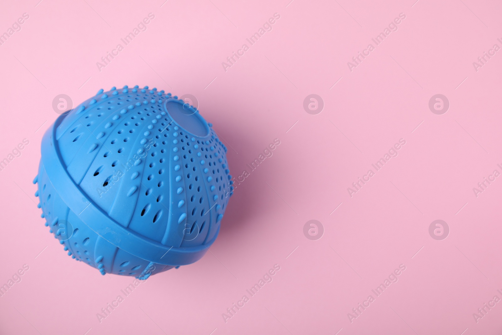 Photo of Laundry dryer ball on pink background, top view. Space for text