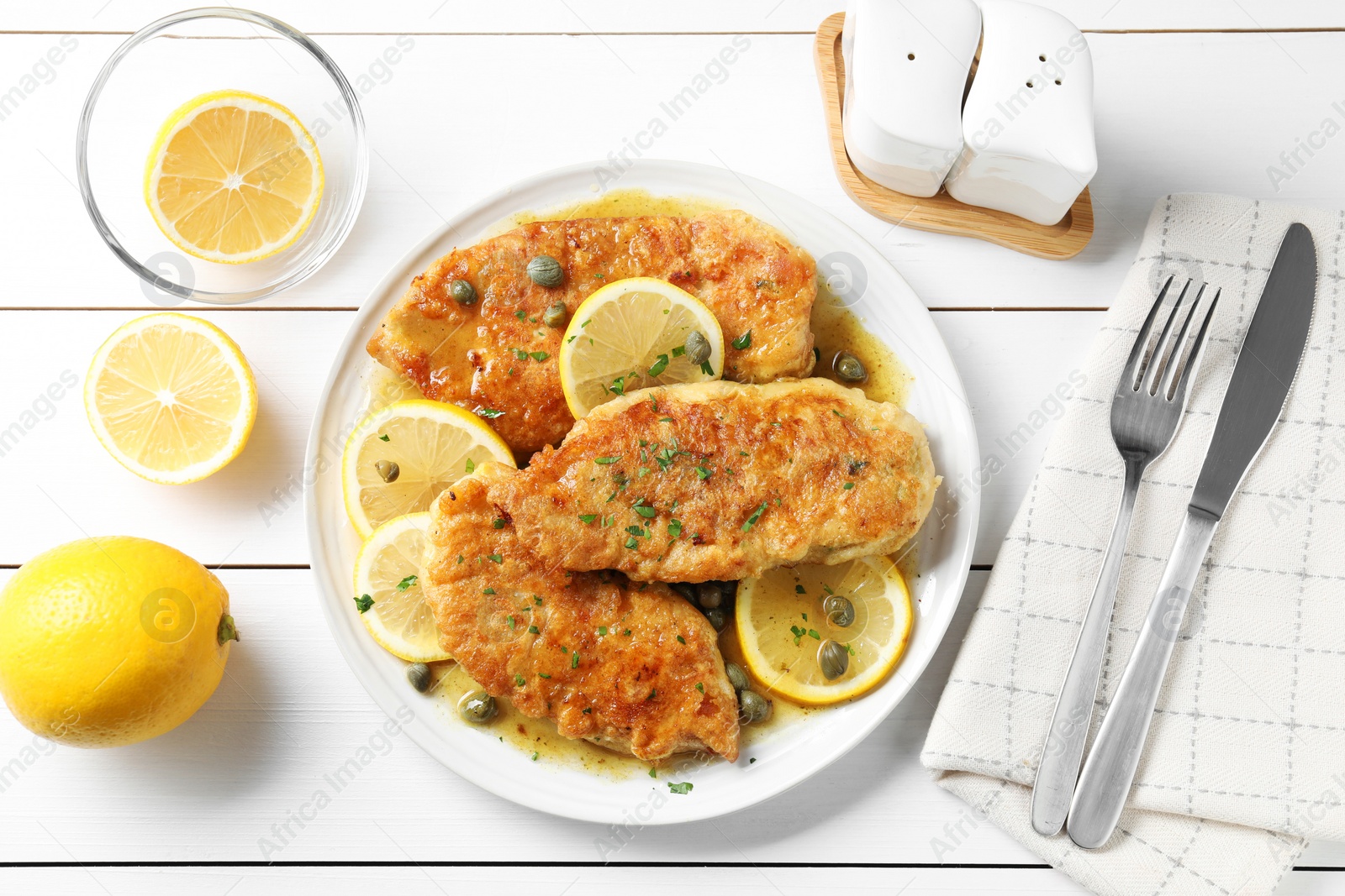 Photo of Delicious chicken piccata served on white wooden table, flat lay