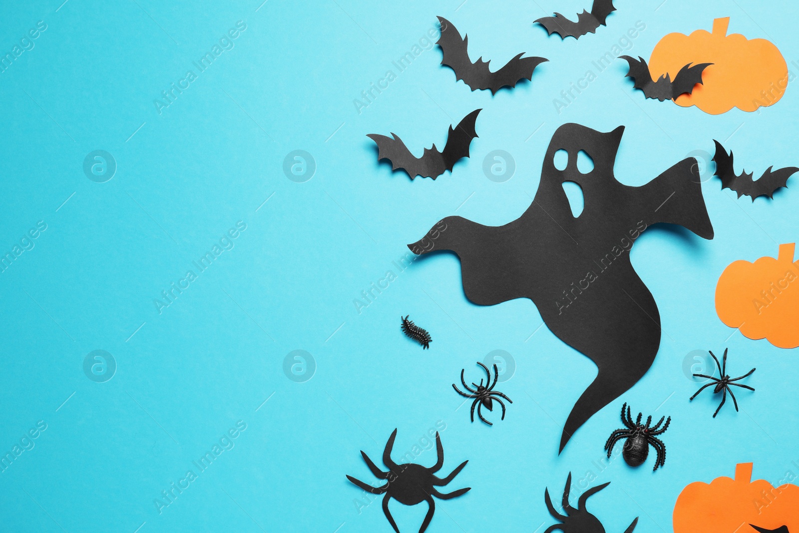 Photo of Flat lay composition with paper ghost, bats and pumpkins on light blue background, space for text. Halloween celebration