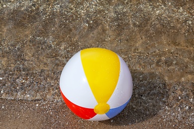 Photo of Bright inflatable beach ball on sandy beach near sea