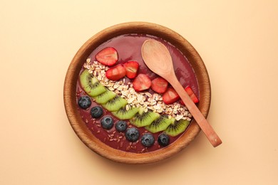 Photo of Bowl of delicious smoothie with fresh blueberries, strawberries, kiwi slices and oatmeal on color background, top view