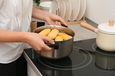 Photo of Woman preparing corn in stewpot on stove, closeup