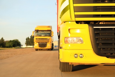 Modern yellow trucks on country road, closeup. Space for text