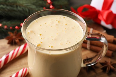 Photo of Glass of delicious eggnog on wooden table, closeup