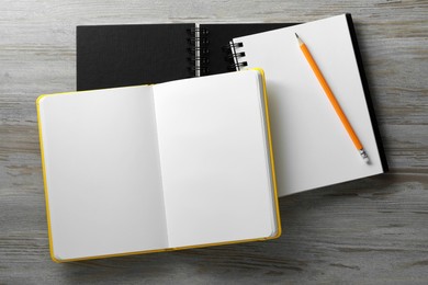 Photo of Stylish notebooks and pencil on white wooden table, flat lay