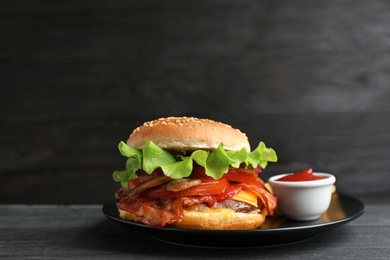 Plate with tasty burger and sauce on wooden table