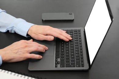 Photo of Woman working on laptop at black desk in office, closeup