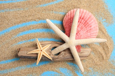 Photo of Piece of wood with beautiful starfishes, shell and sand on blue background, flat lay