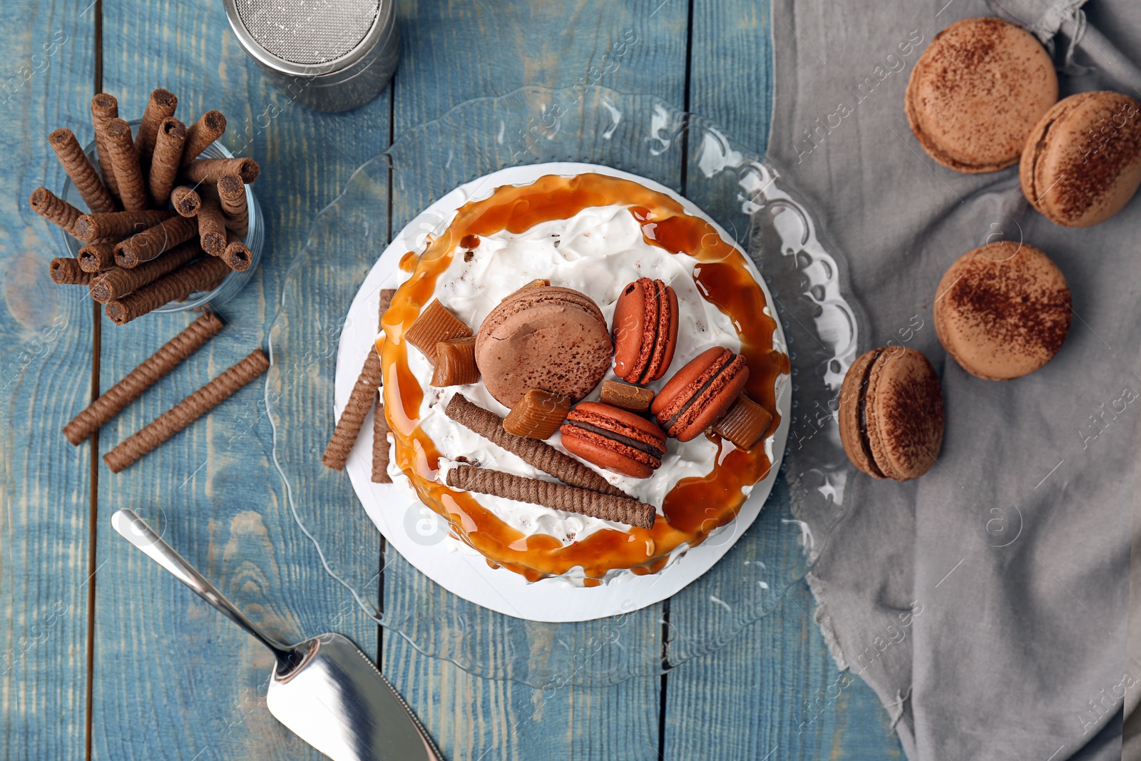 Photo of Delicious homemade cake with caramel sauce and cookies on table, top view