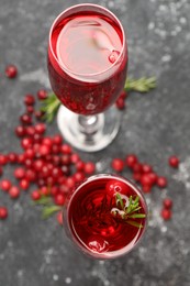 Photo of Tasty cranberry cocktail with rosemary in glasses on gray table, above view