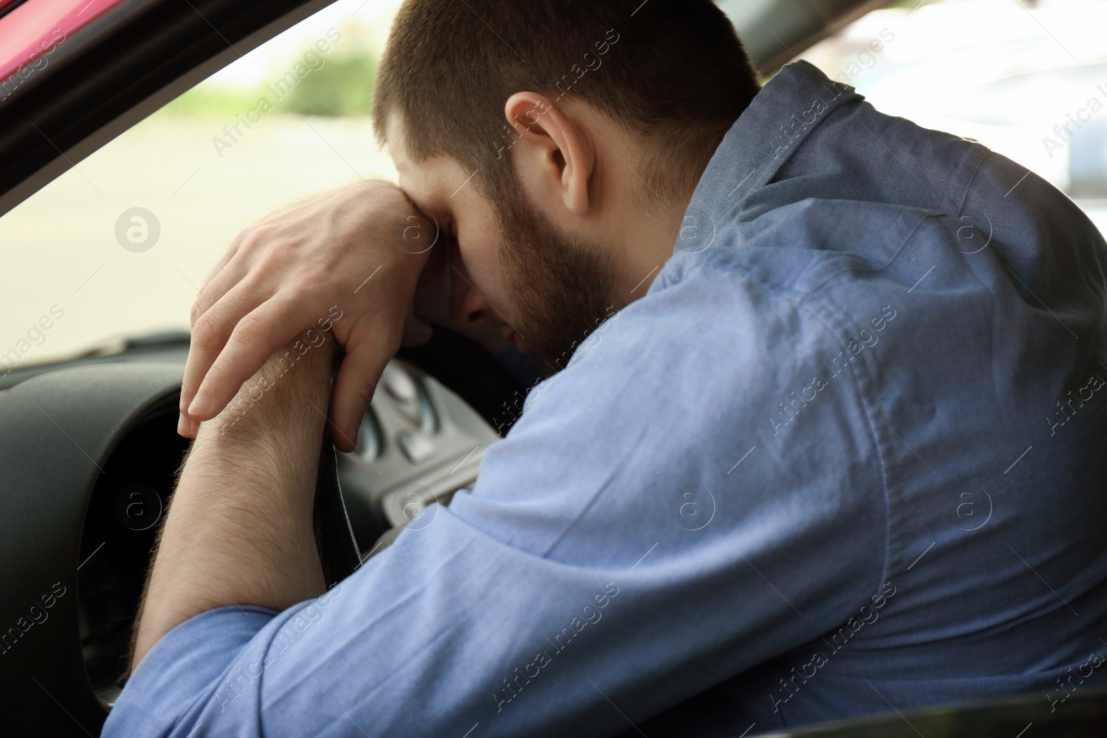 Photo of Tired man sleeping on steering wheel in his car