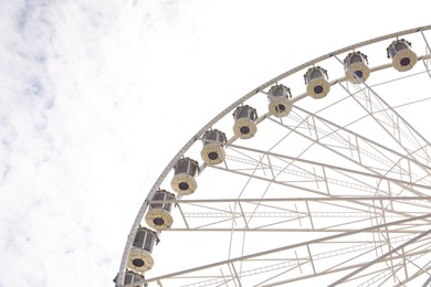 Beautiful Ferris wheel against cloudy sky, low angle view. Space for text