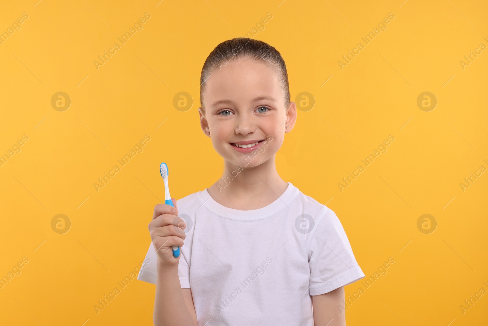 Photo of Happy girl holding toothbrush on yellow background