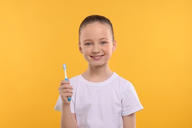Photo of Happy girl holding toothbrush on yellow background