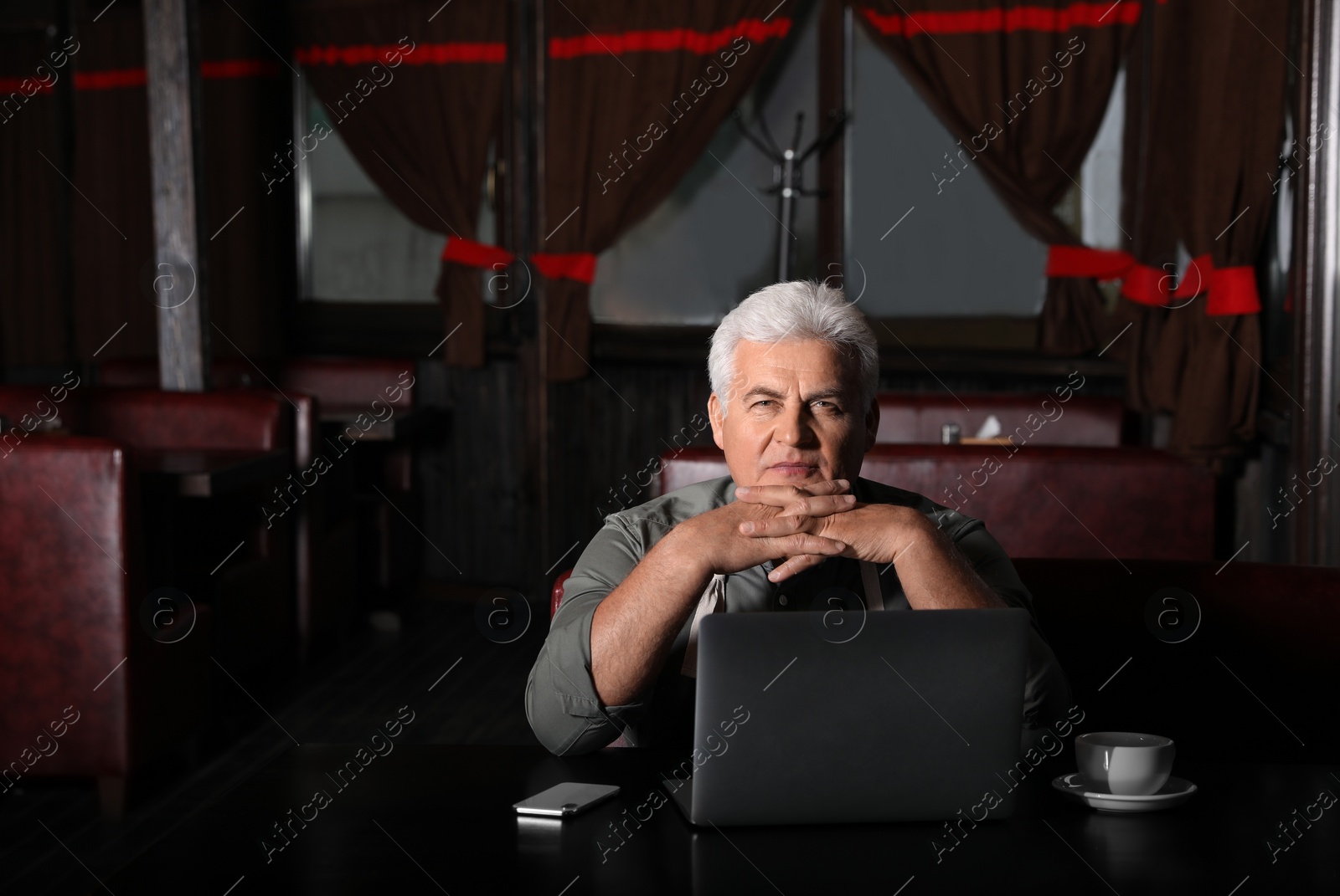 Photo of Senior business owner working with laptop in his restaurant