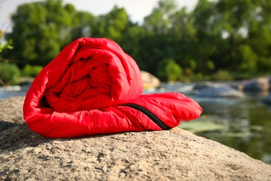 Rolled sleeping bag near lake on sunny day