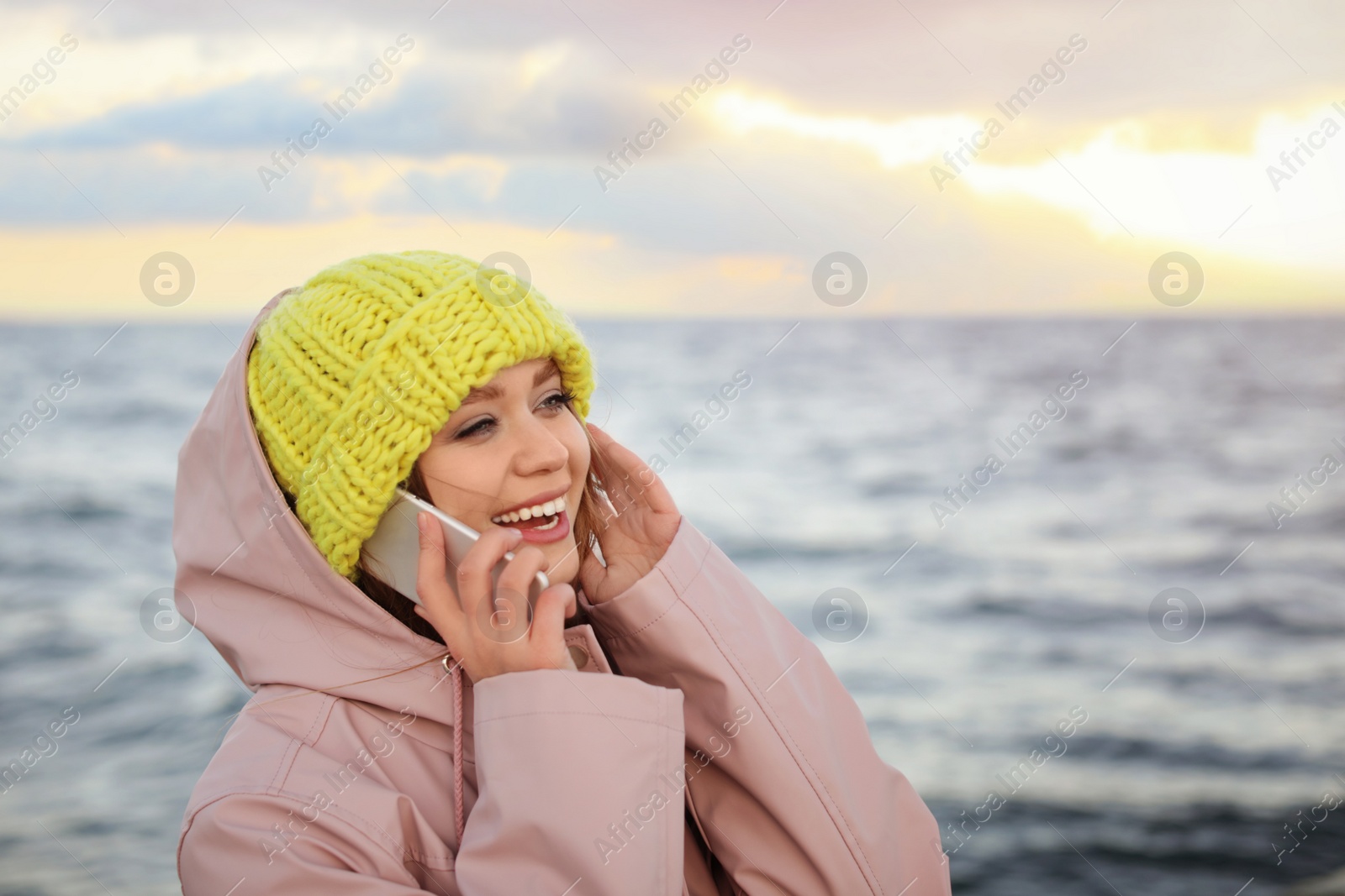 Photo of Young woman talking on mobile phone near sea