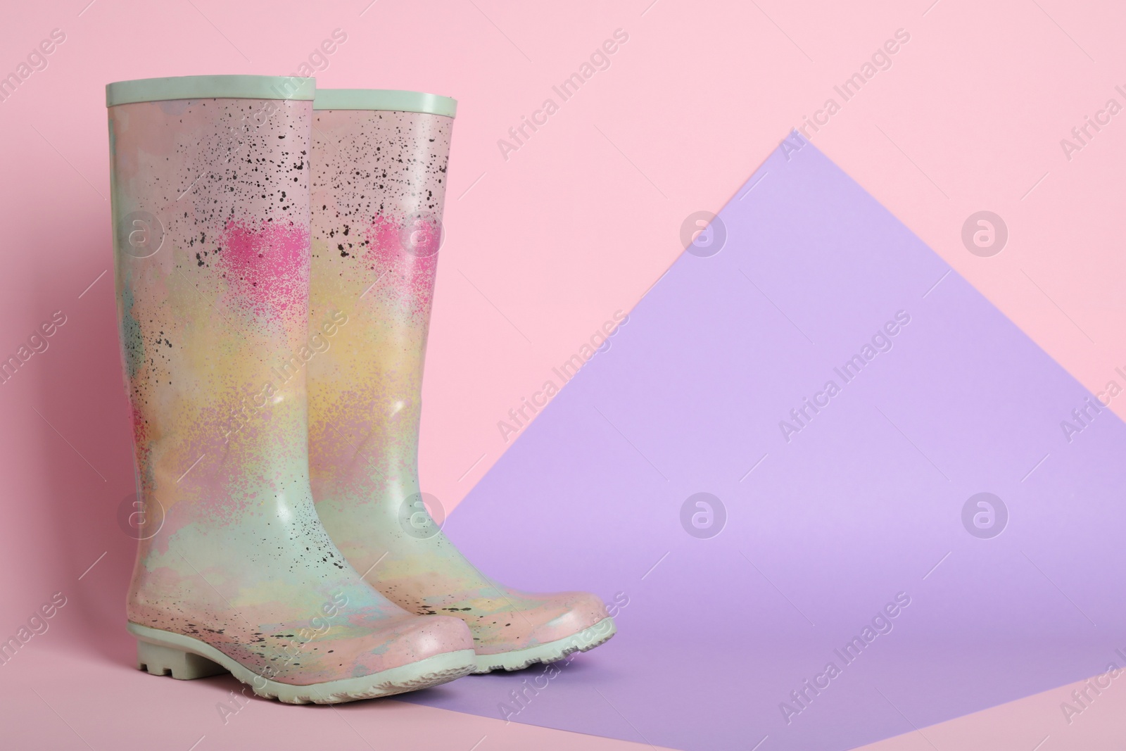 Photo of Pair of rubber boots on color background. Space for text