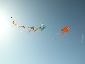Photo of Bright rainbow kites in blue sky, low angle view