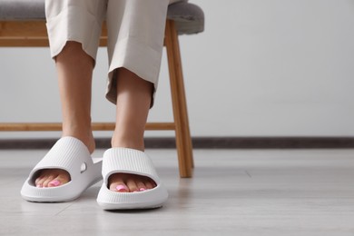 Photo of Woman wearing comfortable rubber slippers indoors, closeup. Space for text