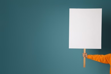 Woman holding blank sign on light blue background, closeup. Space for design