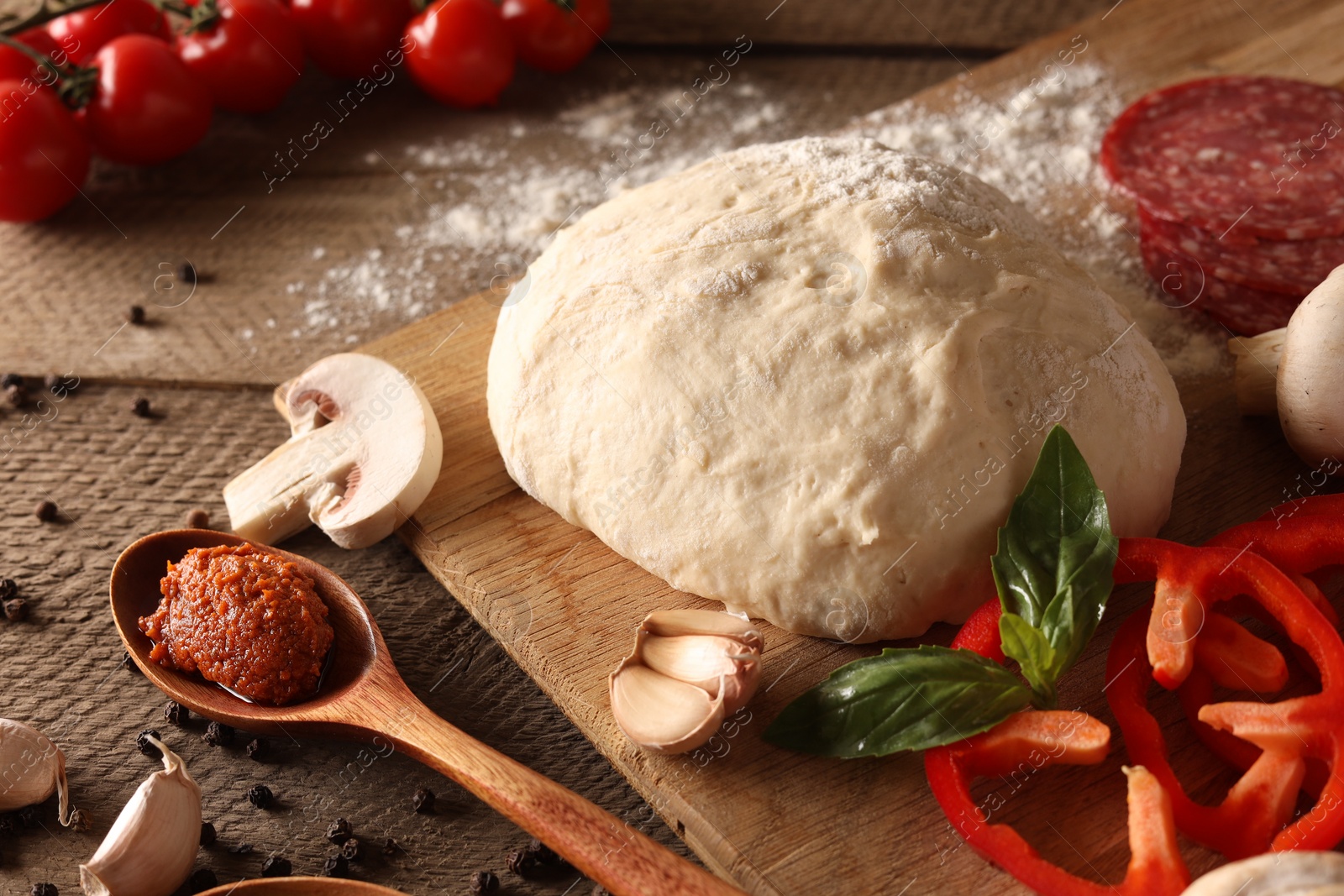 Photo of Pizza dough and products on wooden table, closeup