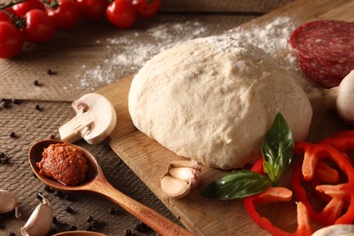 Photo of Pizza dough and products on wooden table, closeup