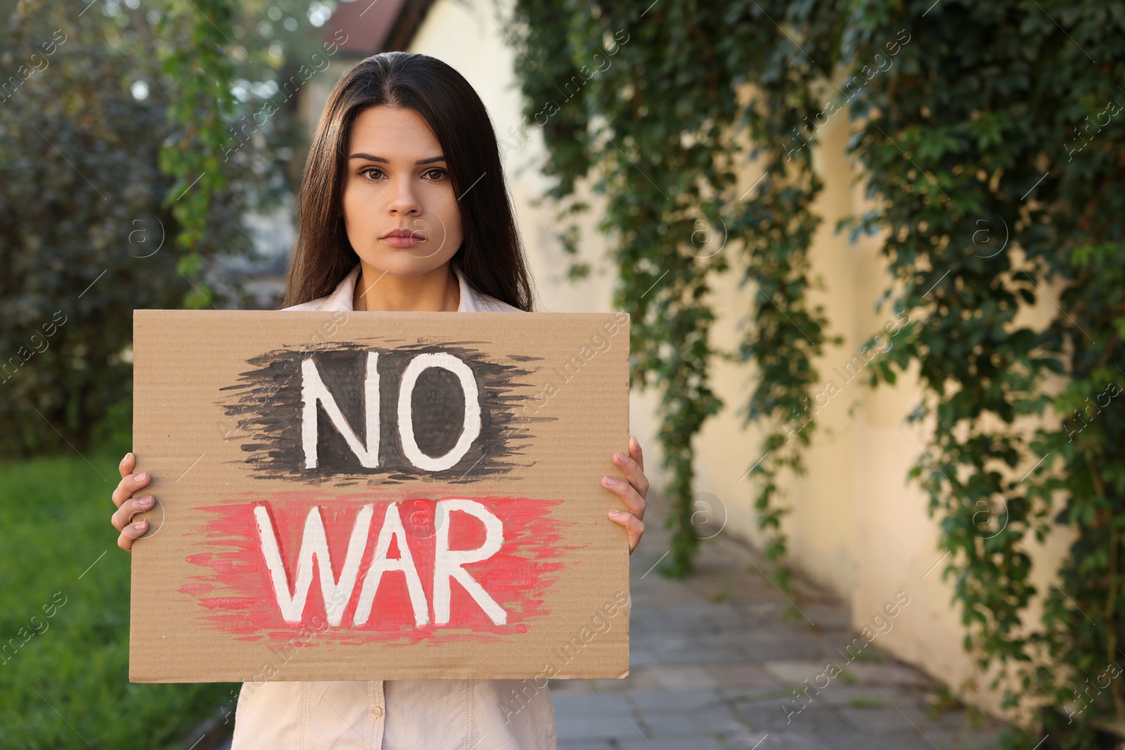 Photo of Sad woman holding poster with words No War outdoors. Space for text