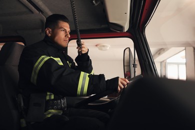 Photo of Firefighter using radio set while driving fire truck
