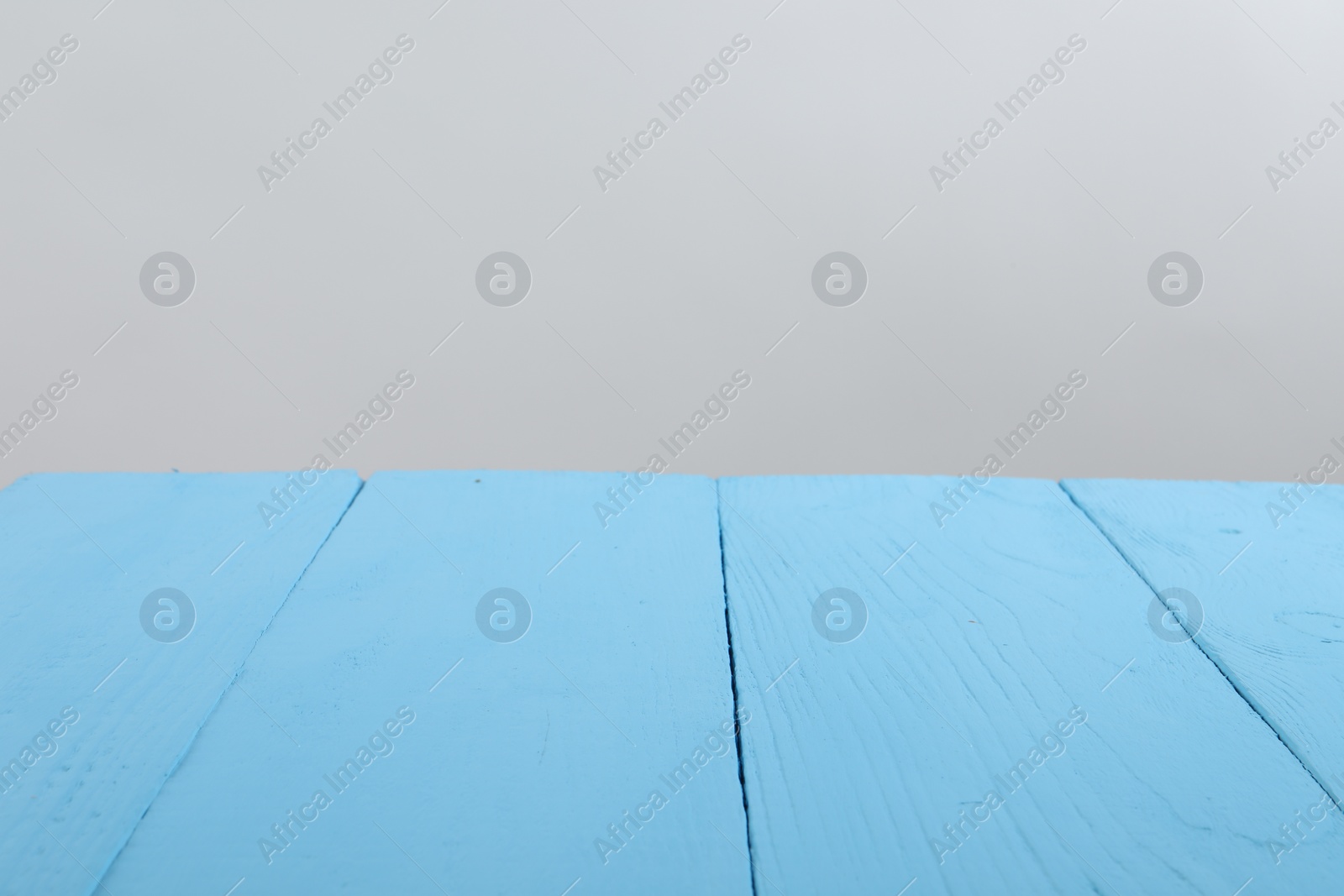 Photo of Empty light blue wooden surface on white background. Space for text