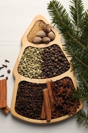 Different spices, nuts and fir branches on white wooden table, flat lay