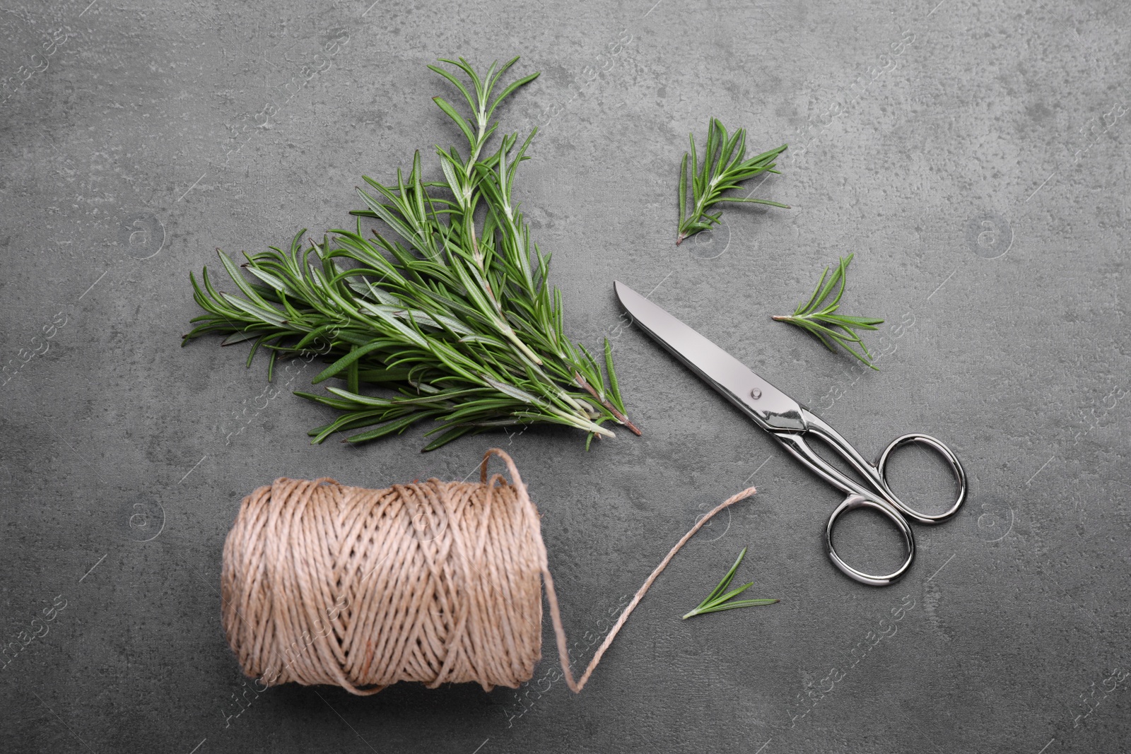 Photo of Sprigs of rosemary, scissors and twine on black background, flat lay