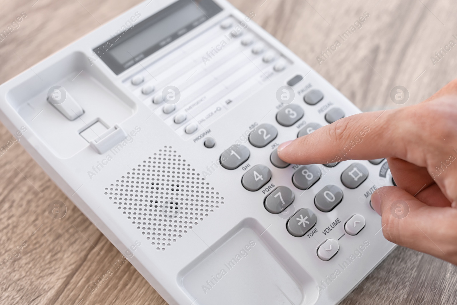 Photo of Man dialing number on telephone at table