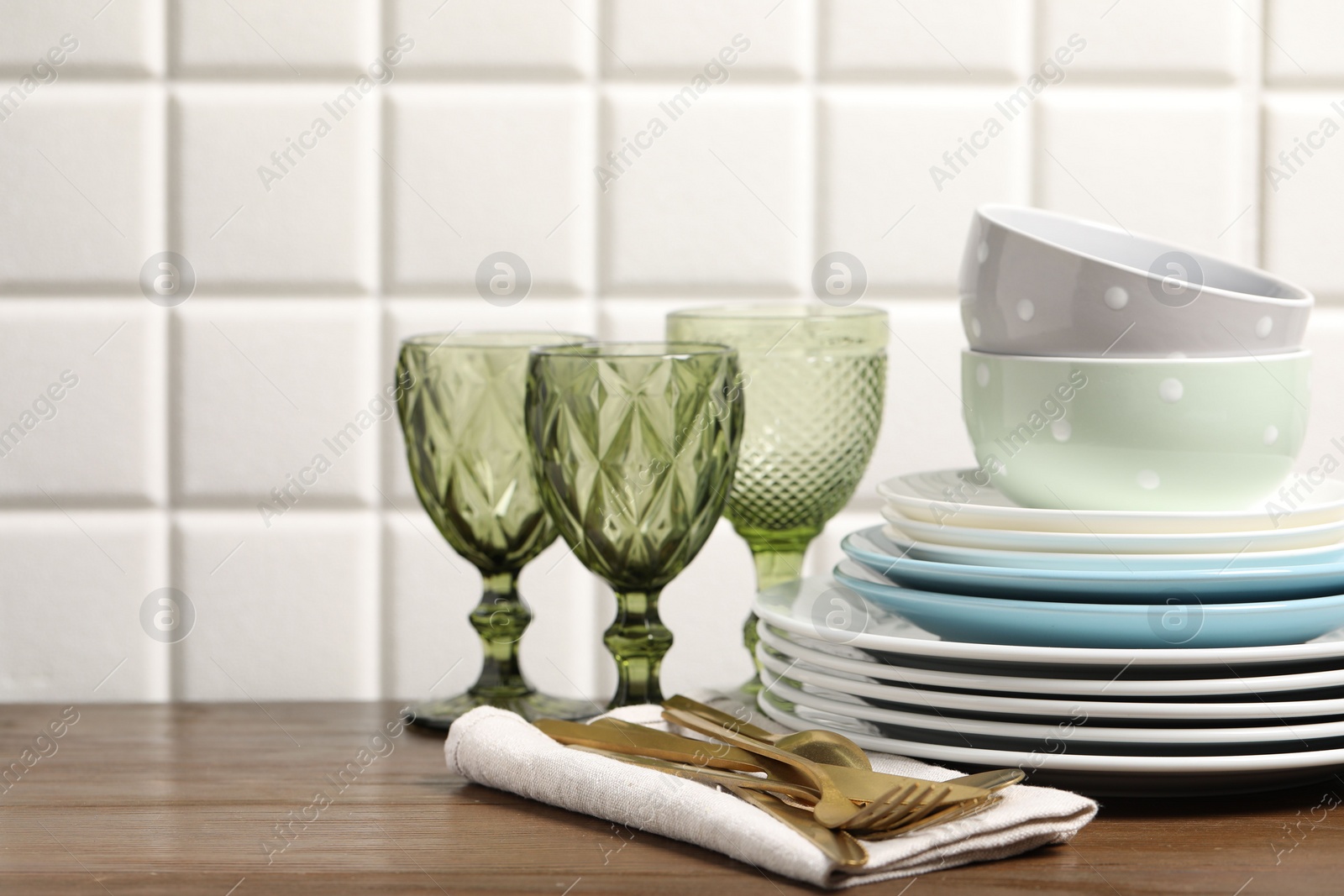 Photo of Beautiful ceramic dishware, glasses and cutlery on wooden table, space for text