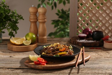 Photo of Stir-fry. Tasty noodles with meat and vegetables served on wooden table