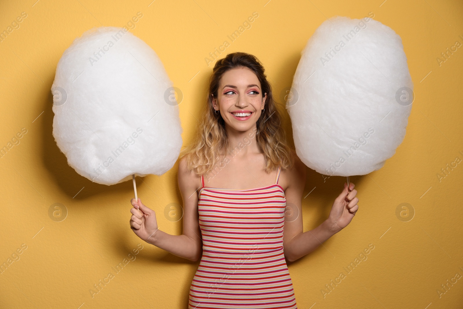 Photo of Portrait of pretty young woman with cotton candy on yellow background