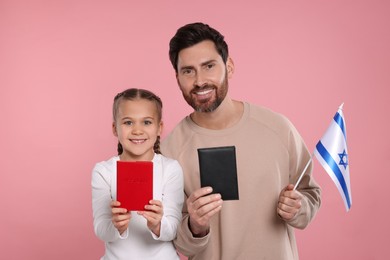 Photo of Immigration. Happy man with his daughter holding passports and flag of Israel on pink background
