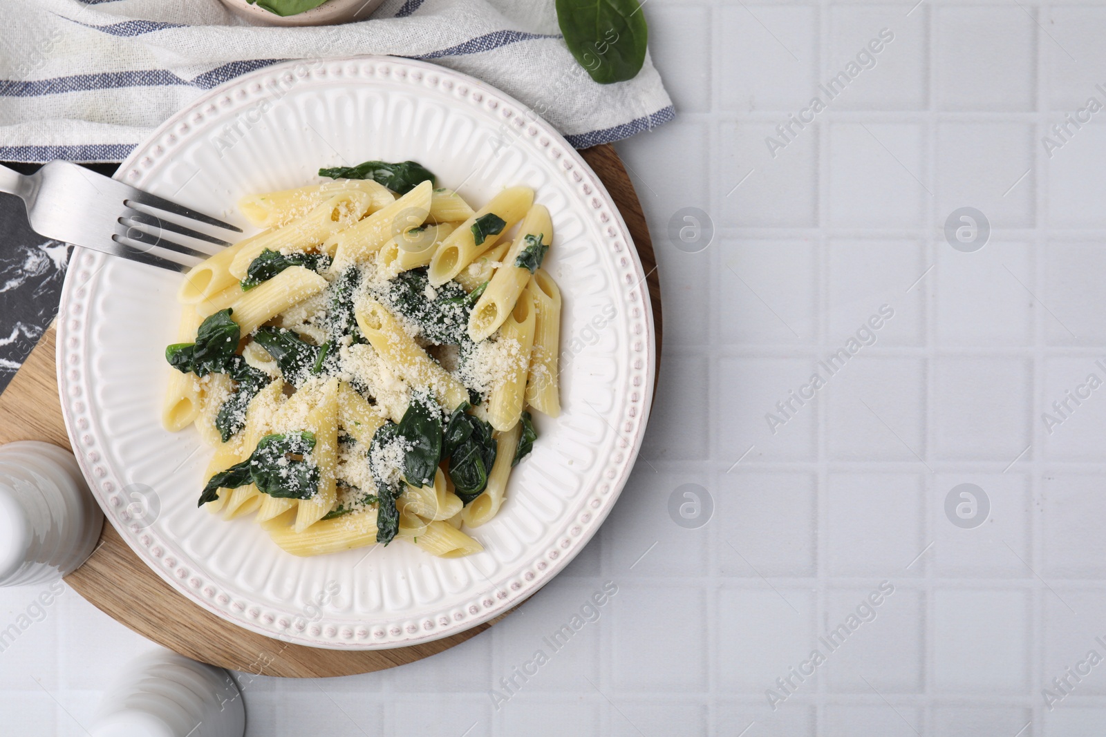 Photo of Tasty pasta with spinach and cheese served on white tiled table, flat lay. Space for text