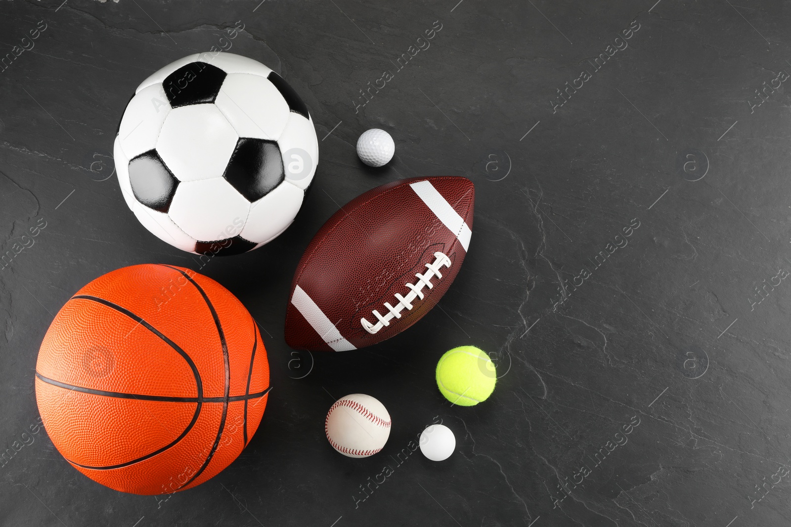 Photo of Many different sports balls on dark gray background, flat lay. Space for text