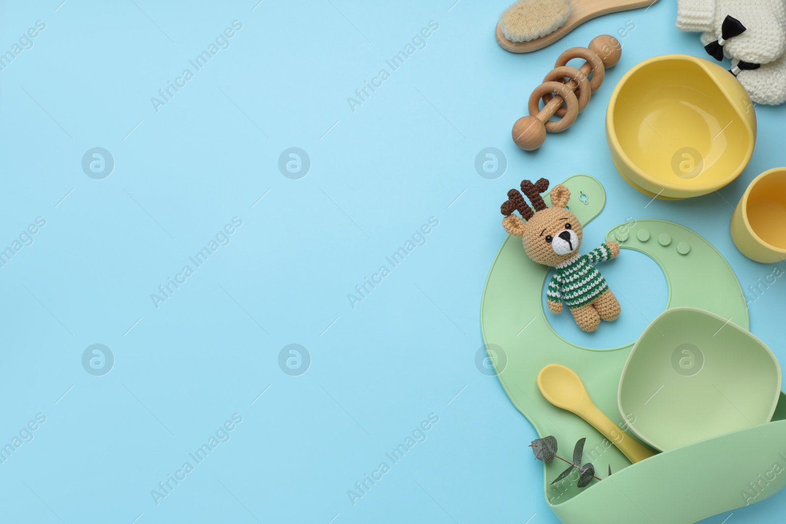 Photo of Flat lay composition with baby feeding accessories and bib on light blue background, space for text