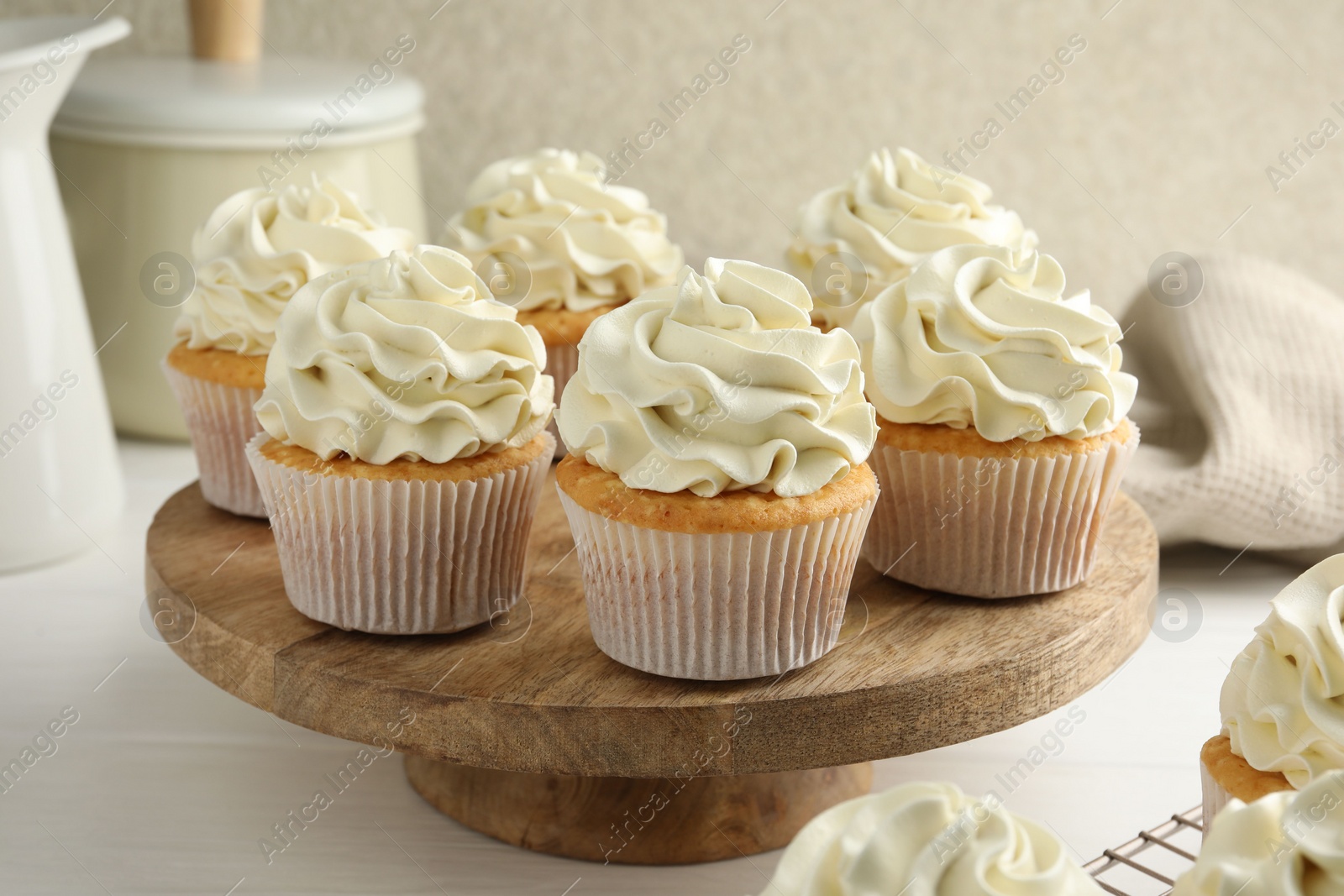 Photo of Tasty vanilla cupcakes with cream on white wooden table