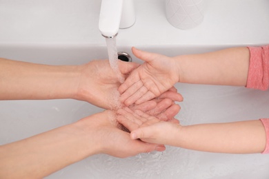 Mother and daughter washing hands in bathroom at home, closeup