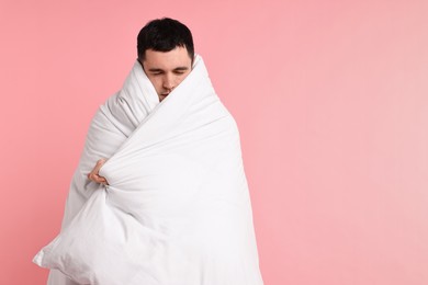 Happy man wrapped in blanket on pink background, space for text