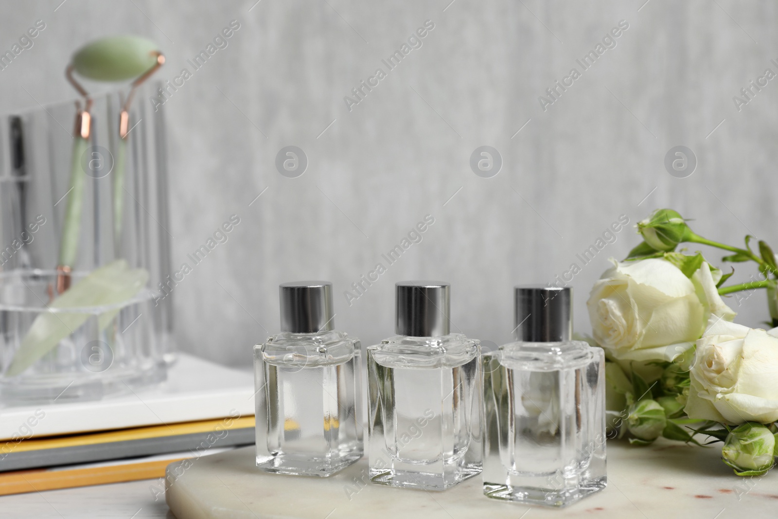 Photo of Perfumes and rose flowers on marble board
